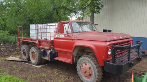 1994 Ford Bronco - This red flatbed truck, likely from the 1970s, is equipped with multiple large tanks on its bed.