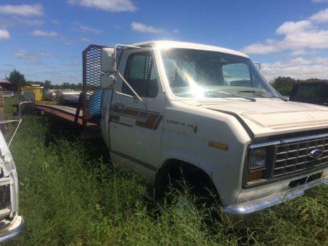1994 Ford Bronco - A white Ford Econoline truck sits in a grassy field under a blue sky with scattered clouds.