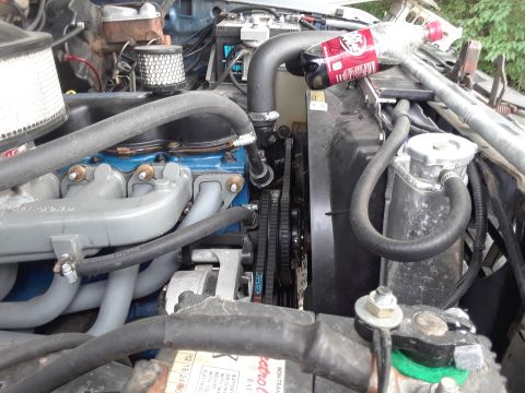 1985 Ford Bronco - Close-up view of an engine bay, the radiator, fan, and various engine components, with a soda bottle resting on the radiator.