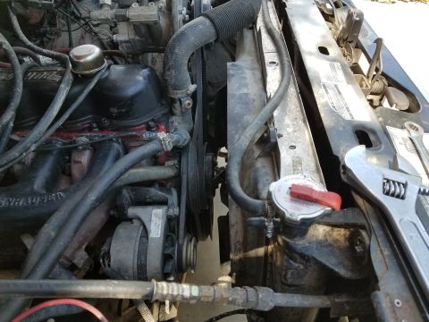 1985 Ford Bronco - An adjustable wrench rests next to the radiator in a vehicle's engine compartment, suggesting maintenance work.