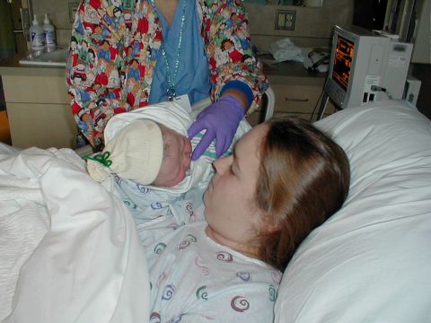 1983 Ford Bronco - A mother gazes at her newborn baby in a hospital room, with a nurse attending.