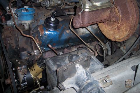 1978 Ford Bronco - Close-up view of an engine bay, showing blue valve covers and a rusty brake booster.