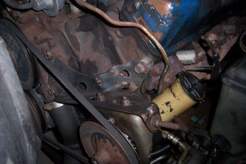 1978 Ford Bronco - Close-up view of engine components, including belts and a fluid reservoir, showing signs of rust and wear.