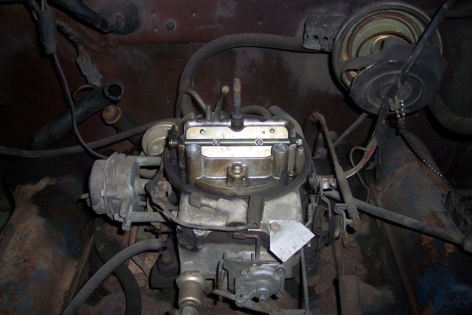 Close-up of a vehicle's carburetor and engine bay components