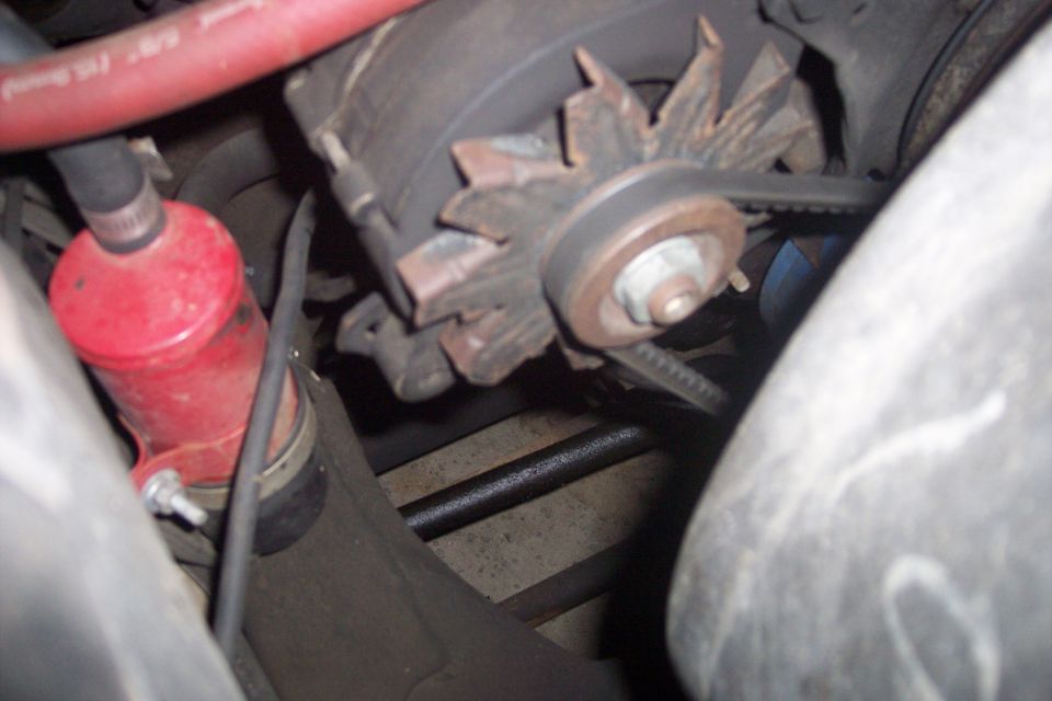 close-up of car alternator with belt and red fluid canister