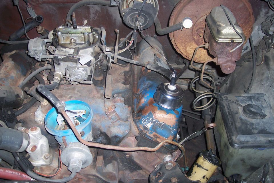 Engine bay showing carburetor, distributor, and brake fluid reservoir