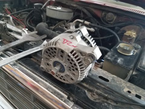 1985 Ford Bronco - Alternator removed from engine bay, resting on the grille with tools nearby.