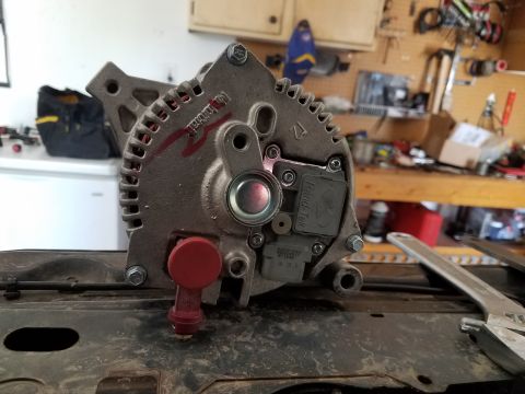 1985 Ford Bronco - Close-up view of an alternator, showing its various components and markings.