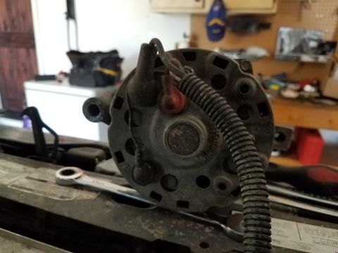 1985 Ford Bronco - Close-up of an alternator with a wrench nearby, suggesting a repair or installation process.