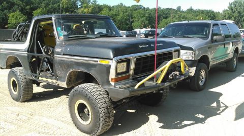 1978 Ford Bronco - This modified Bronco has a roll cage and racing seats, parked next to a modern SUV.