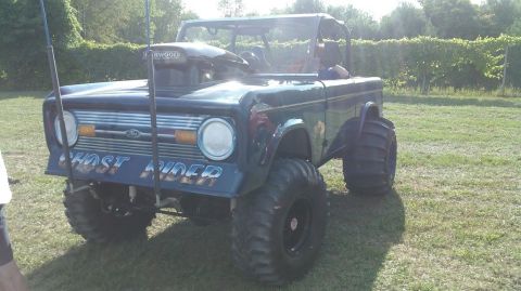 1978 Ford Bronco - Customized 1978 Ford Bronco sits on a grassy field, oversized tires and a prominent air intake.