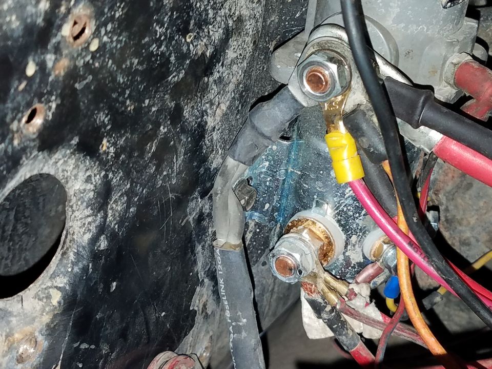 Close-up of electrical connections with wires, bolts, and a blue substance