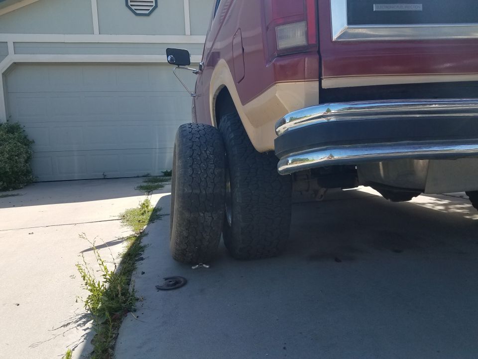 Red and tan Ford Bronco rear quarter panel with chrome bumper and large tires