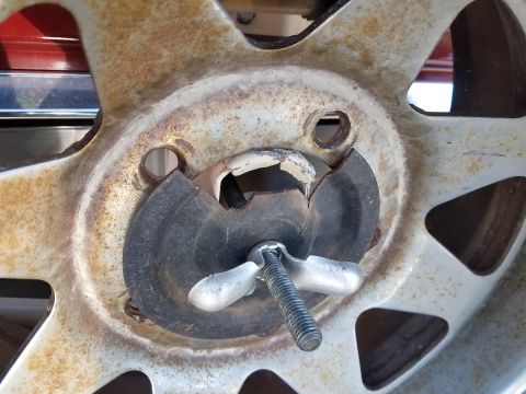 1985 Ford Bronco - The wing nut and bolt are securing a spare tire to a rusty wheel.