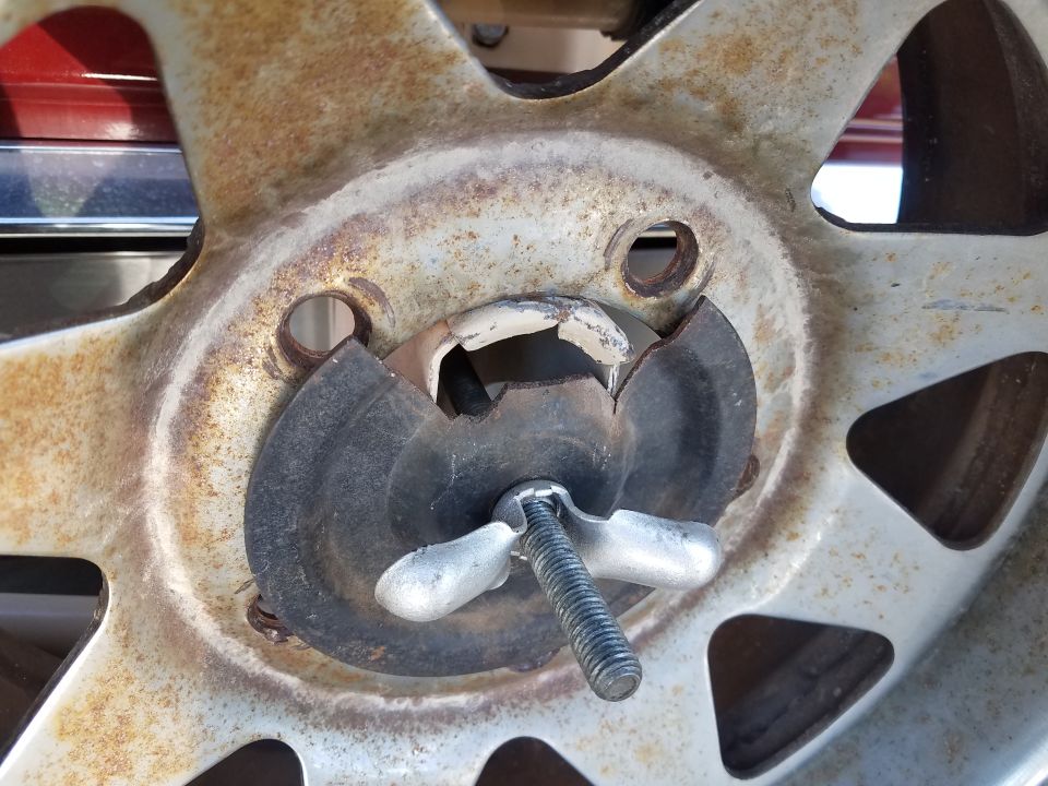 Close-up of a rusty spare tire hold-down wing nut and bolt on a wheel