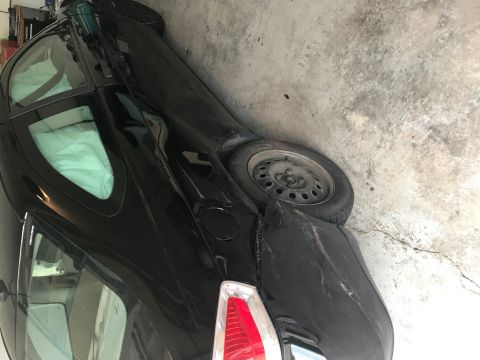2008 Ford Focus - A black hatchback is parked indoors, showing damage to its rear and interior covered for protection.