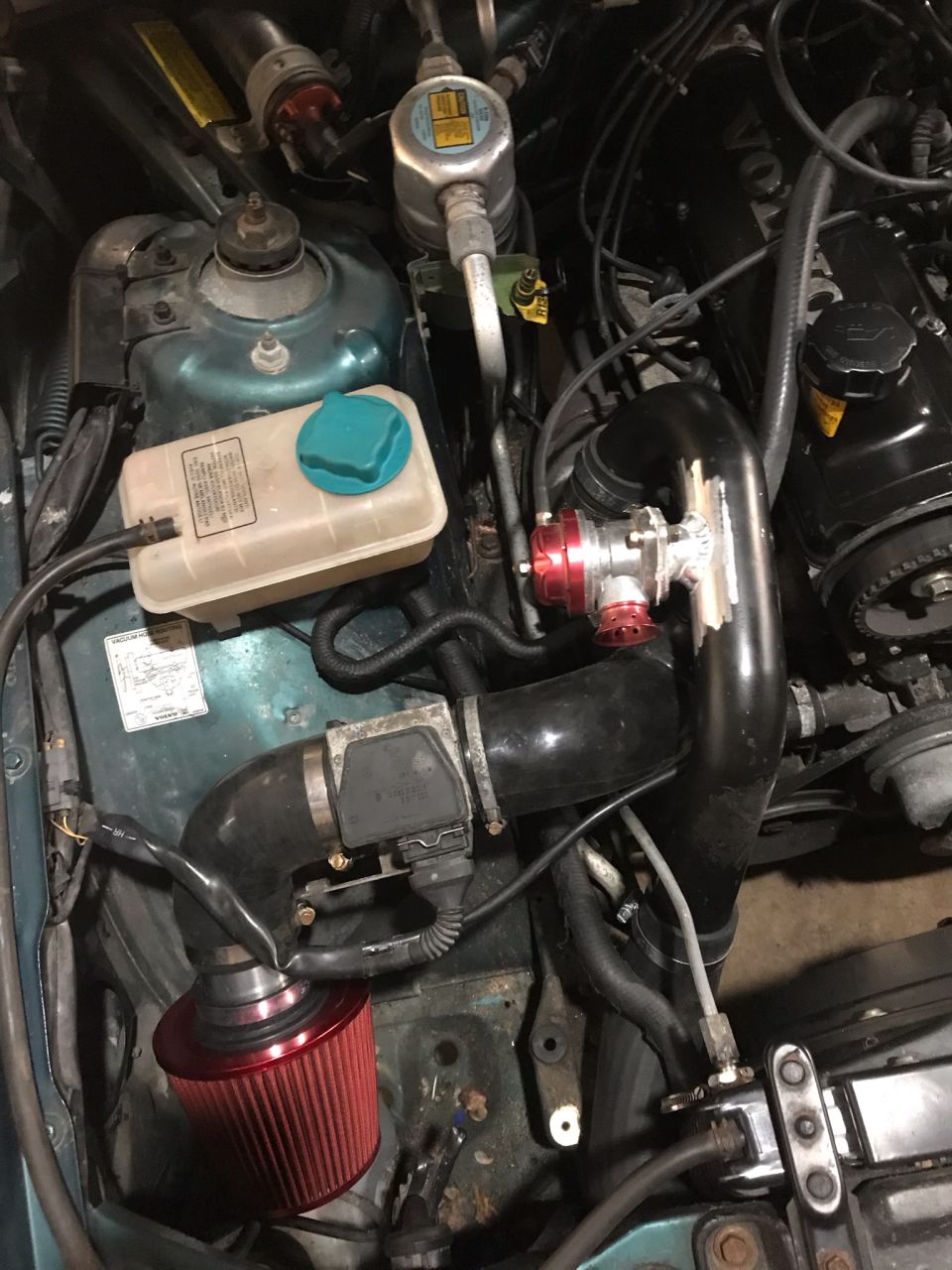 Engine bay showing aftermarket turbo piping, blow-off valve, and air filter