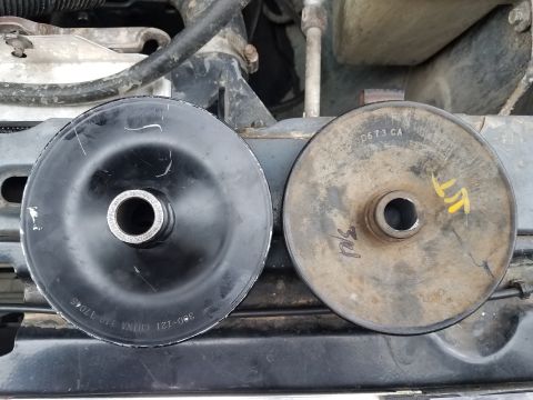 1985 Ford Bronco - A comparison of a new black pulley and an old, weathered pulley is shown in an engine compartment.