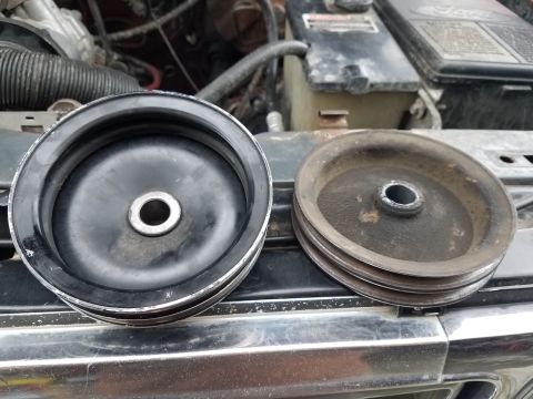 1985 Ford Bronco - Comparing a new pulley to an old, worn pulley in an engine bay.