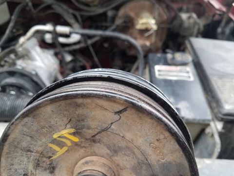 1985 Ford Bronco - Close-up of a damaged pulley in a vehicle's engine bay, with visible cracks and markings.