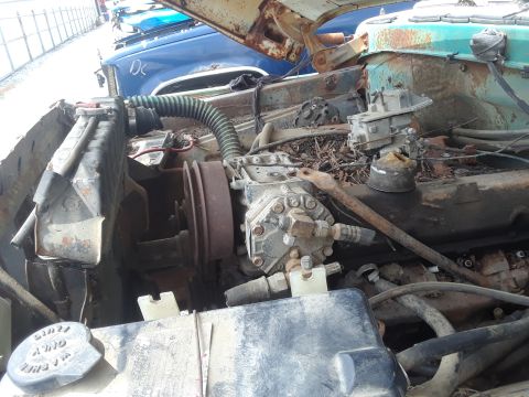 1994 Ford Bronco - Close-up view of a vehicle's engine compartment, showing various engine components and a glimpse of another vehicle in the background.