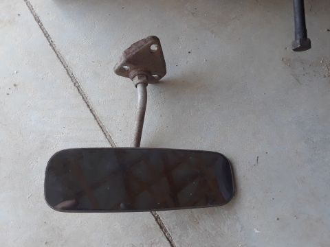 1994 Ford Bronco - A detached interior rearview mirror with a heavily rusted mounting bracket is shown on a concrete surface.