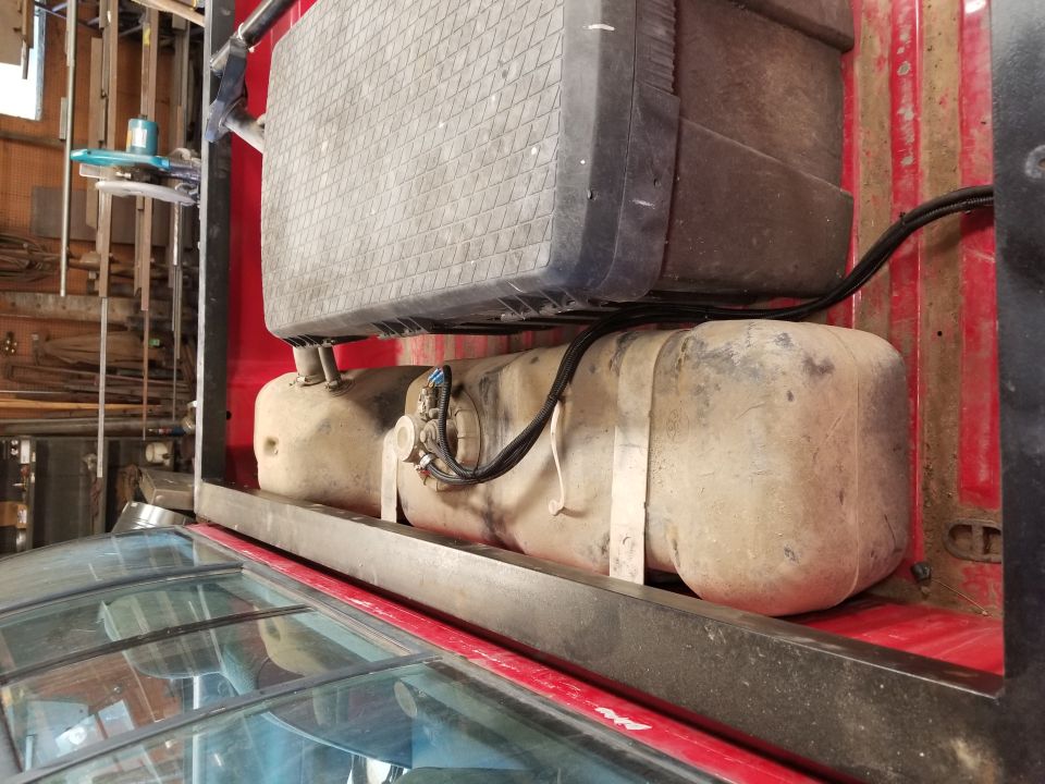 Truck bed with a large auxiliary fuel tank mounted above the main fuel tank