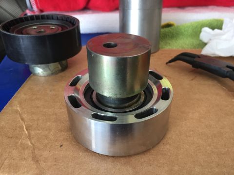 2000 Lotus Esprit - Close-up of automotive pulleys, one metal and one black with teeth, on a workbench.
