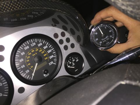 2000 Lotus Esprit - Close-up of a vehicle's interior dashboard, showing various gauges including a speedometer, temperature gauge, and a turbo gauge being held.