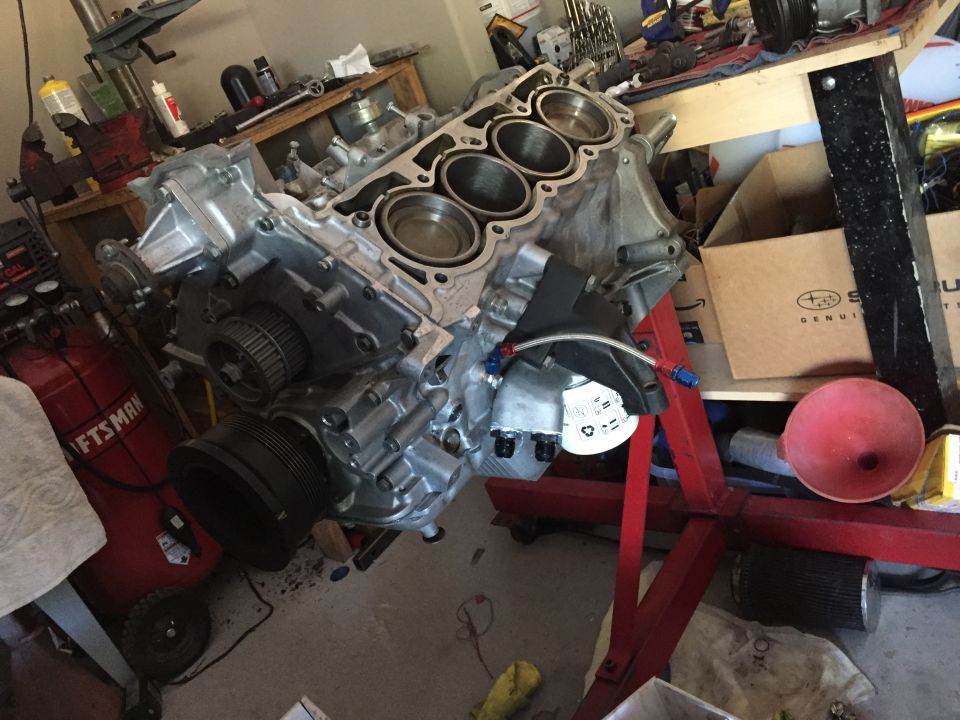 engine block on a red stand in a garage, with an air compressor nearby