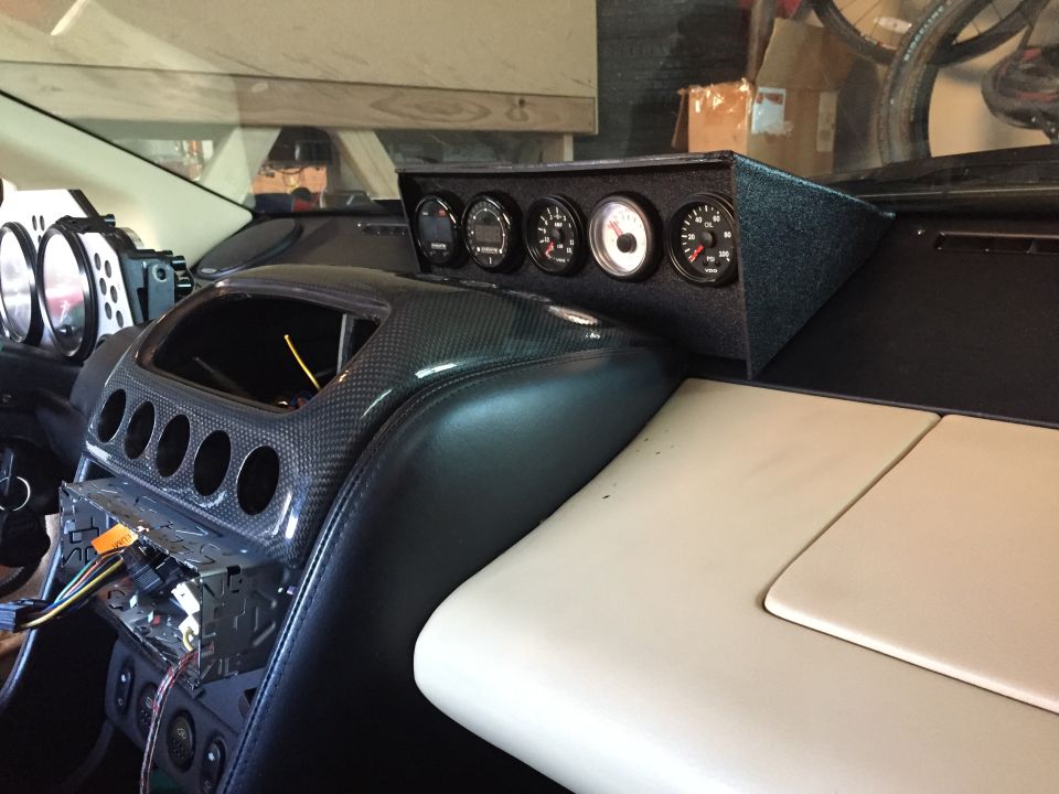 car interior showing dashboard with multiple gauges and carbon fiber trim