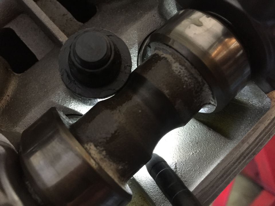 Close-up of a metal engine component with a bolt and a rotating shaft