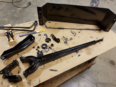 1978 Ford Bronco - Various black painted suspension and steering parts are arranged on a workbench, ready for assembly.