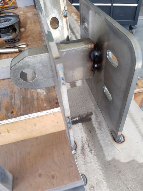 1978 Ford Bronco - A custom-fabricated steel bracket, likely for a vehicle, is shown up close on a workbench.