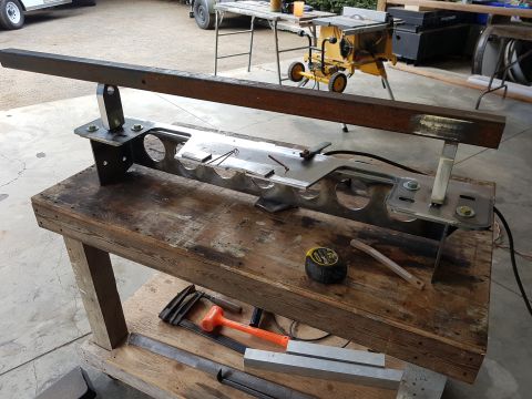 1978 Ford Bronco - A custom fabricated metal part, likely for a vehicle, rests on a workbench alongside various tools.