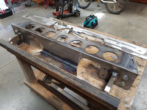 1978 Ford Bronco - A custom metal part is shown on a workbench, with tools and other metal pieces nearby.