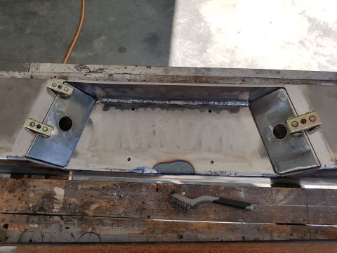 1978 Ford Bronco - A custom metal part, likely for a vehicle build, is shown with welded seams and attached brass brackets.