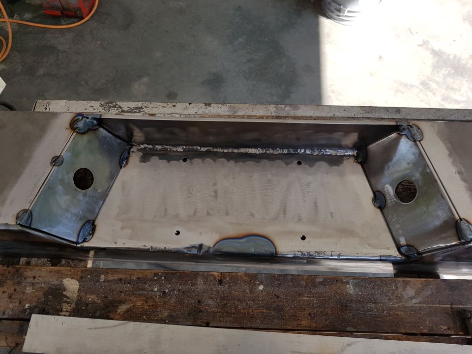 Welded metal part with angled plates and circular cutouts