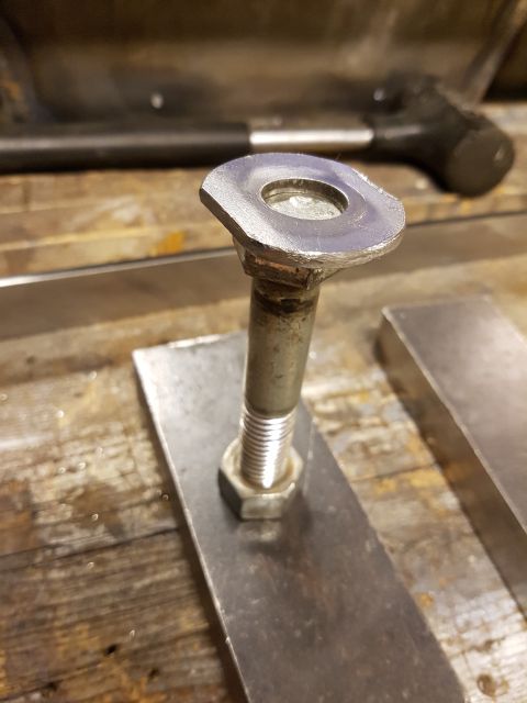 1978 Ford Bronco - A close-up view of a bolt, washer, and nut assembly on metal plates, with a hammer visible in the background.