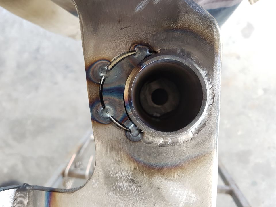 Close-up of a metal part with visible welds and a circular opening