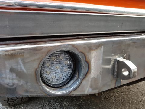 1978 Ford Bronco - Close-up of a custom metal bumper a round LED light and a tow hook, with visible welding marks.