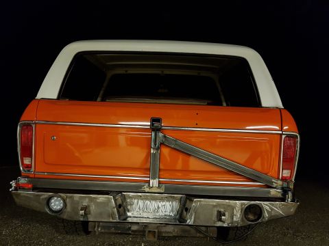 1978 Ford Bronco - The rear of an orange and white 1978 Ford Bronco is shown with a custom fabricated bumper and tire mount.