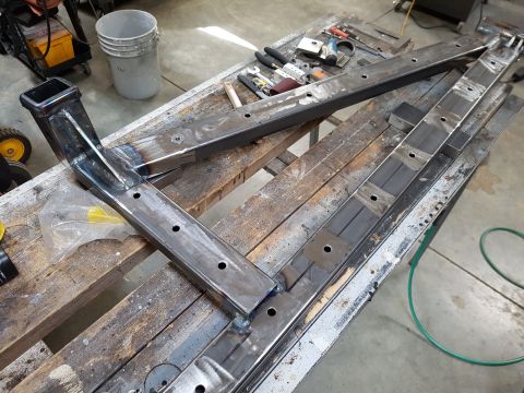 1978 Ford Bronco - Metal frame components are laid out on a workbench, ready for assembly or modification.