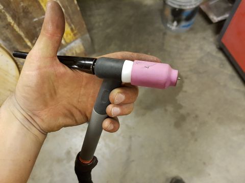 1978 Ford Bronco - A welding torch with a pink ceramic nozzle is held by a person's hand.