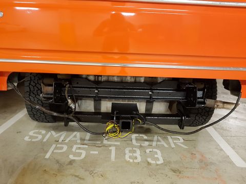 1978 Ford Bronco - Rear view of an orange vehicle showing its hitch, exhaust, and tires parked in a spot marked 'SMALL CAR'.