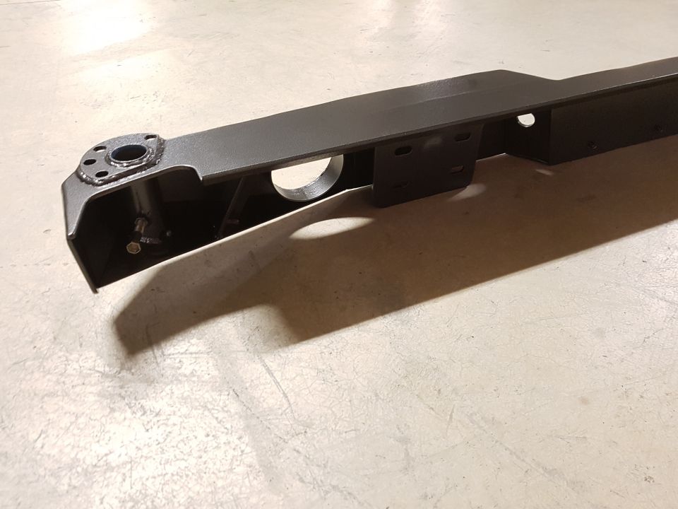 Close-up of a dark metal suspension component with mounting holes