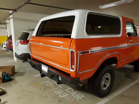 1978 Ford Bronco - Orange and white 1978 Ford Bronco seen from the rear in a parking garage.