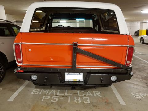 1978 Ford Bronco - Orange 1978 Ford Bronco parked in a garage with a white hardtop and custom rear bumper.