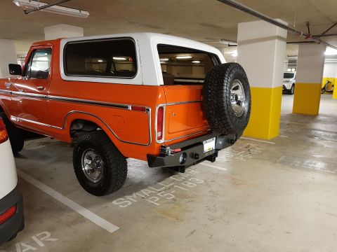1978 Ford Bronco - Rear view of an orange 1978 Ford Bronco with a white removable hardtop and a spare tire carrier.