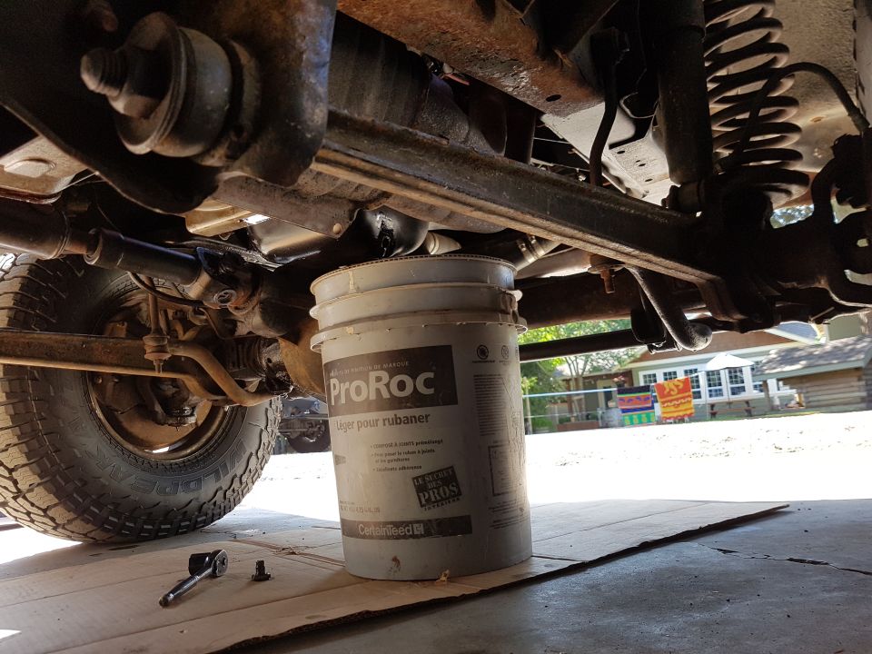 Undercarriage of a vehicle with a bucket supporting the frame. Visible suspension and tire